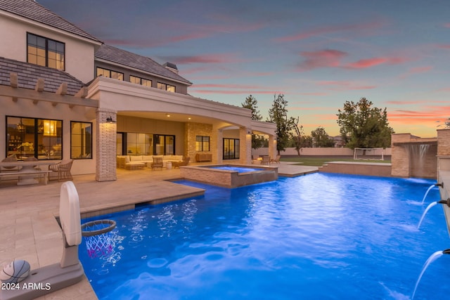 pool at dusk featuring a patio area, a pool with connected hot tub, and outdoor lounge area