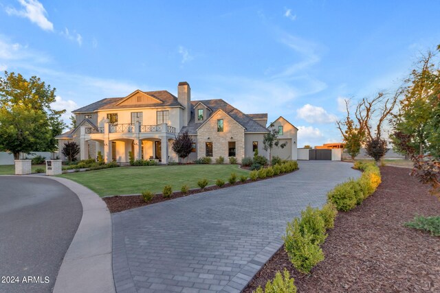 view of front of house with a balcony and a front lawn