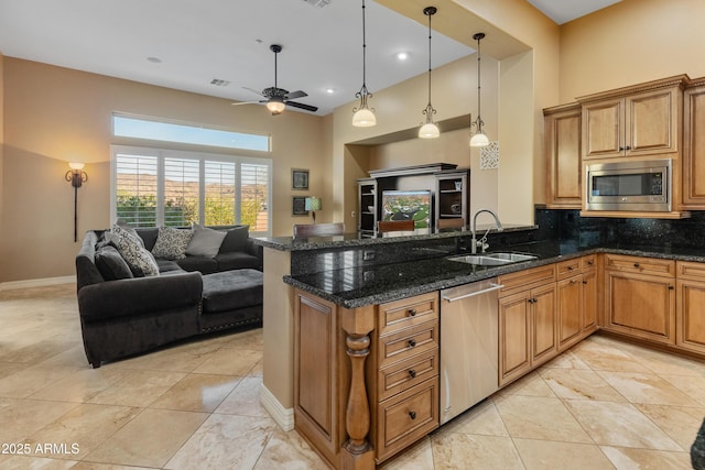 kitchen with appliances with stainless steel finishes, dark stone counters, decorative backsplash, sink, and ceiling fan