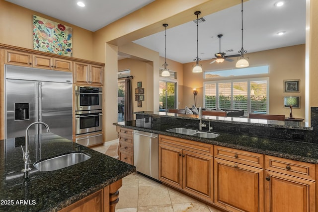 kitchen with sink, dark stone countertops, hanging light fixtures, and stainless steel appliances