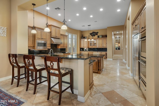 kitchen with a kitchen bar, backsplash, stainless steel appliances, and pendant lighting