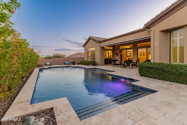 pool at dusk featuring a patio