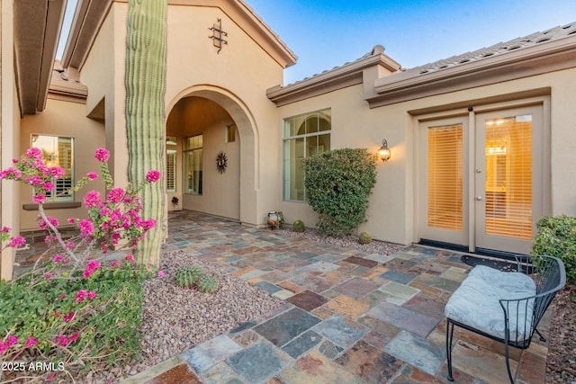 view of exterior entry with french doors and a patio area