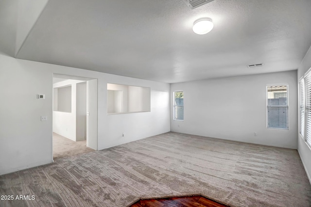 carpeted spare room with a textured ceiling