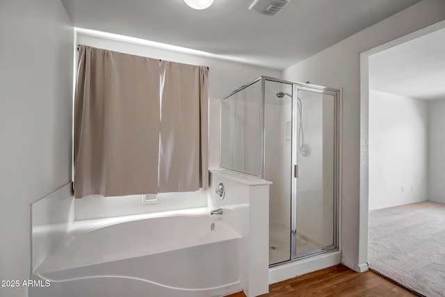 bathroom with hardwood / wood-style flooring and shower with separate bathtub