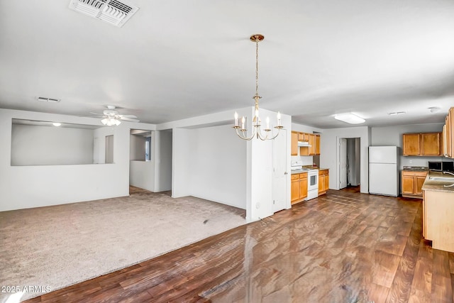 kitchen featuring sink, hanging light fixtures, dark hardwood / wood-style floors, white appliances, and ceiling fan with notable chandelier