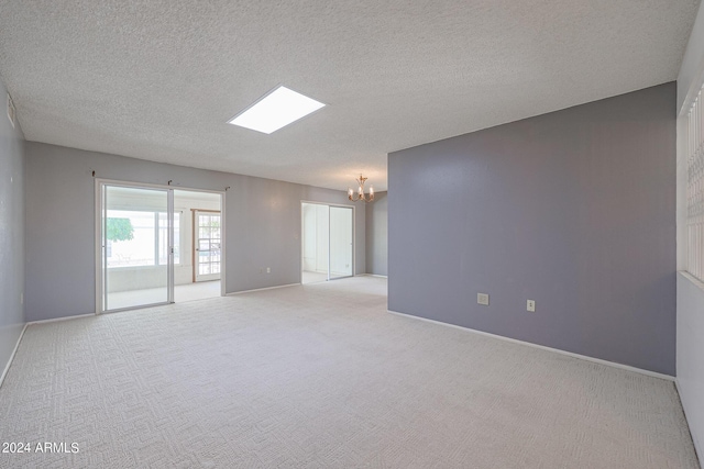 carpeted spare room with a chandelier and a textured ceiling