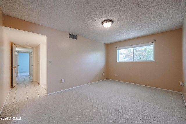 empty room with light colored carpet and a textured ceiling