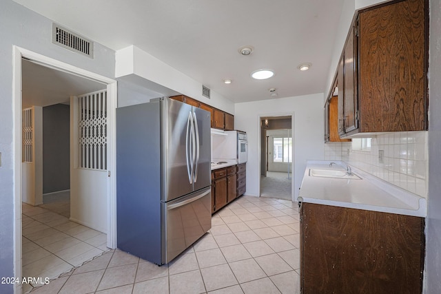 kitchen featuring light tile patterned floors, white appliances, tasteful backsplash, and sink