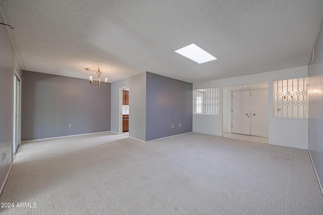 carpeted empty room with a chandelier and a textured ceiling