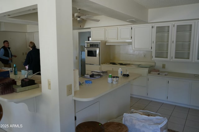 kitchen featuring white cabinetry, light tile patterned floors, ceiling fan, kitchen peninsula, and white appliances