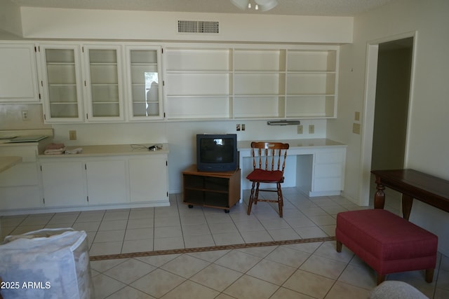 kitchen featuring built in desk, white cabinets, and light tile patterned flooring