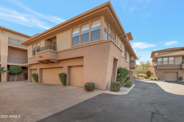 view of property exterior featuring a garage, decorative driveway, and stucco siding