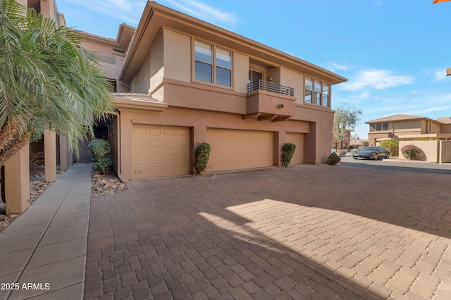 multi unit property with an attached garage, decorative driveway, and stucco siding