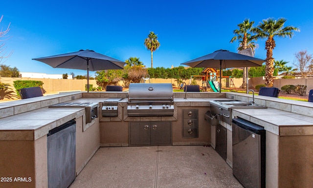 view of patio featuring a grill, a playground, and exterior kitchen