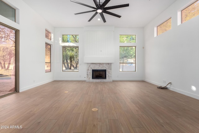 unfurnished living room with baseboards, wood finished floors, a ceiling fan, and a fireplace