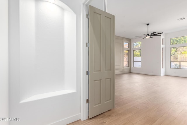 hall with baseboards, light wood-style flooring, and visible vents