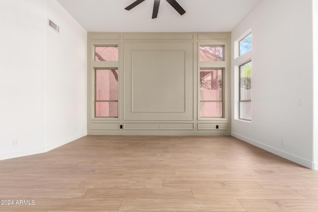 spare room with light wood-type flooring, visible vents, baseboards, and ceiling fan