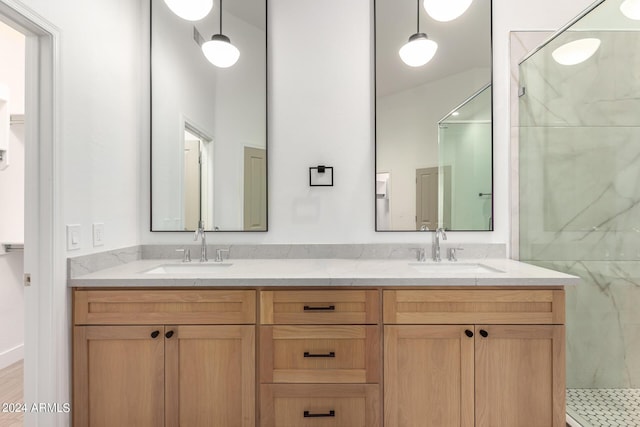 full bathroom with double vanity, a marble finish shower, and a sink