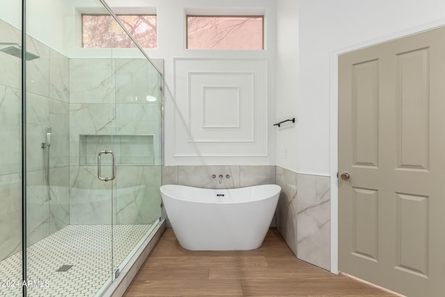bathroom with a stall shower, tile walls, and a freestanding bath