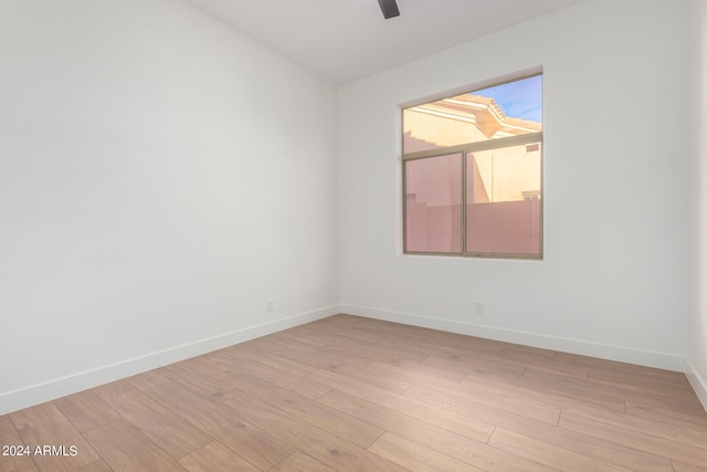 spare room featuring baseboards, light wood-style flooring, and ceiling fan