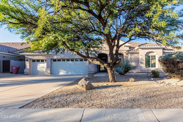 mediterranean / spanish-style house with concrete driveway, an attached garage, stucco siding, and a tiled roof