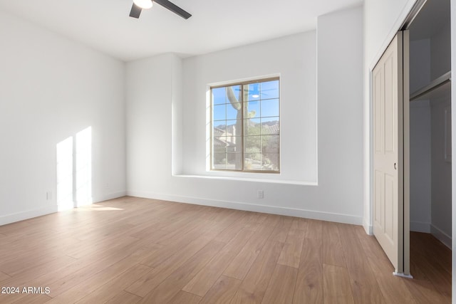 unfurnished bedroom featuring ceiling fan, light wood-style flooring, baseboards, and a closet