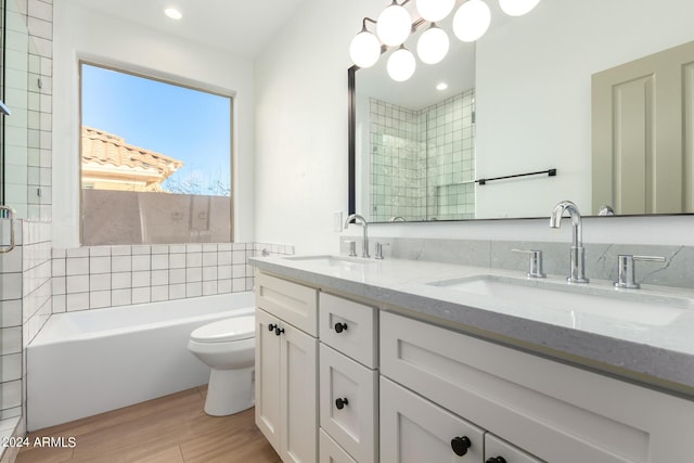 bathroom featuring toilet, tiled shower, a sink, and wood finished floors