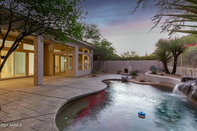 pool at dusk with a patio area, a fenced in pool, and a fenced backyard