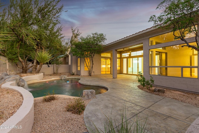 pool at dusk featuring a patio, a fenced in pool, and a fenced backyard