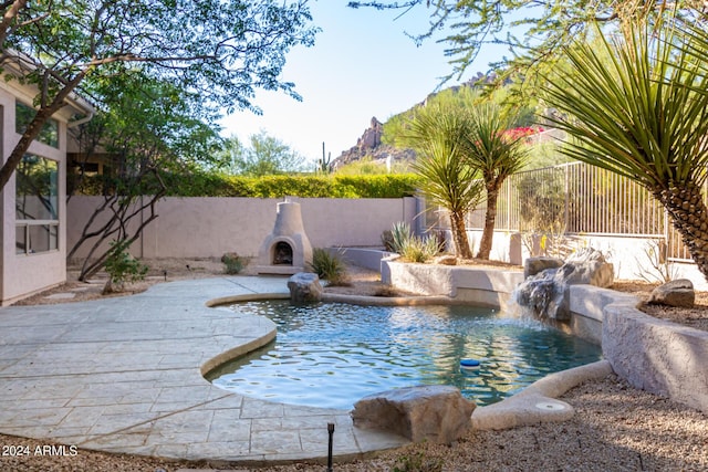 view of swimming pool with a patio area, exterior fireplace, a fenced in pool, and a fenced backyard