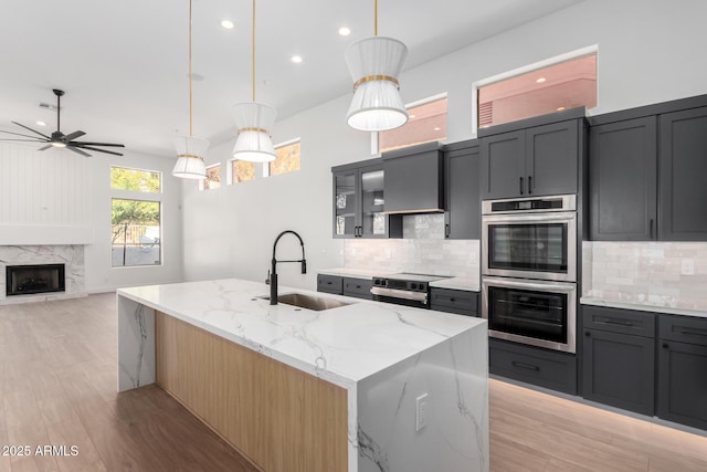 kitchen with stainless steel appliances, ceiling fan, a sink, and decorative backsplash