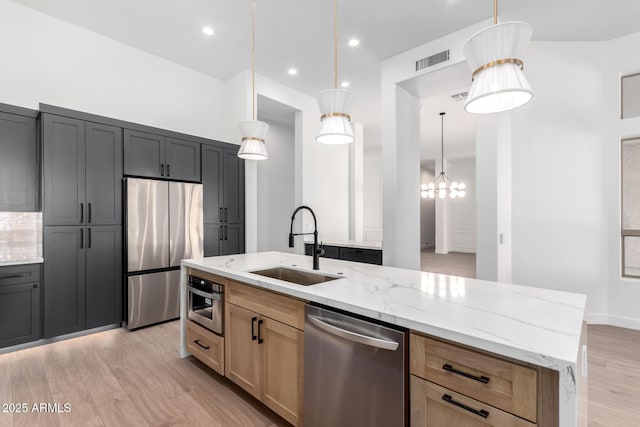 kitchen with a sink, stainless steel appliances, visible vents, recessed lighting, and light stone countertops