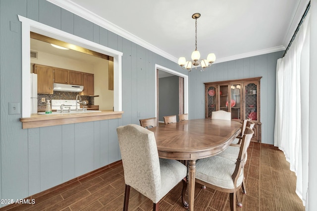 dining area with sink, crown molding, and a chandelier