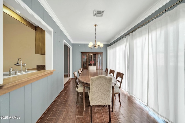 dining area with ornamental molding, sink, and a notable chandelier