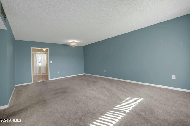 empty room with light colored carpet and a textured ceiling