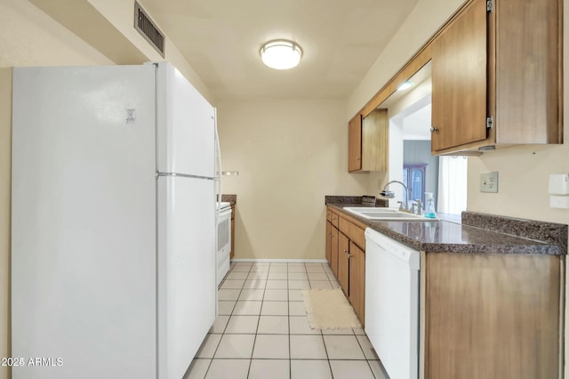 kitchen with white appliances, sink, and light tile patterned floors