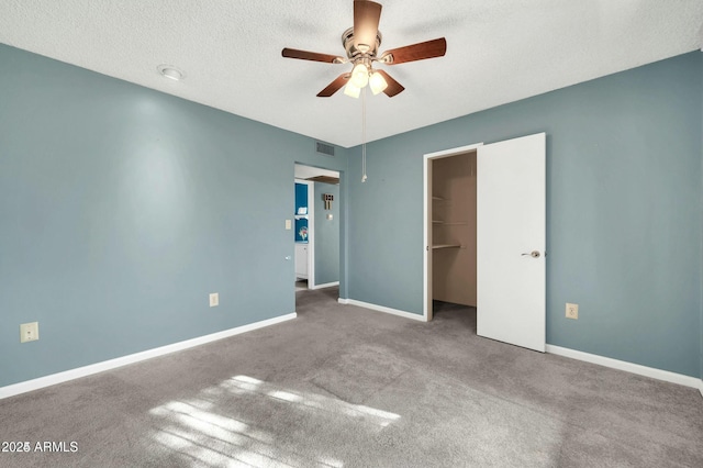 unfurnished bedroom featuring carpet flooring, a walk in closet, ceiling fan, a textured ceiling, and a closet