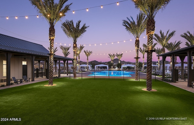 yard at dusk featuring a community pool and a patio area