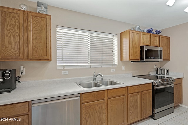 kitchen with appliances with stainless steel finishes, light tile patterned flooring, and sink