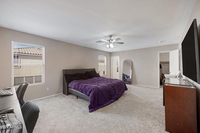 bedroom with multiple windows, ceiling fan, light colored carpet, and a textured ceiling