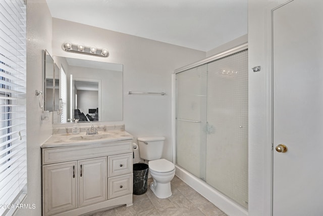 bathroom featuring vanity, toilet, and a shower with shower door