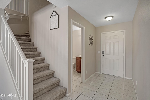 foyer with a textured ceiling and light tile patterned flooring