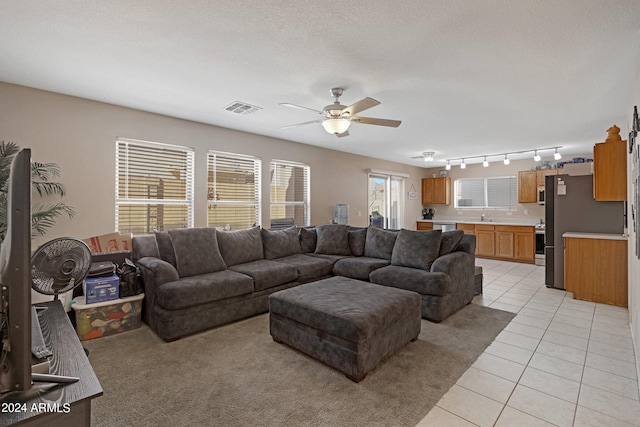 living room featuring a textured ceiling, light tile patterned floors, sink, rail lighting, and ceiling fan