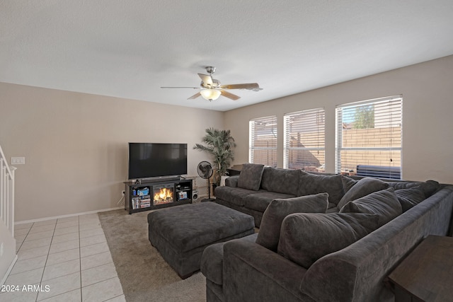 living room with a textured ceiling, light tile patterned floors, and ceiling fan