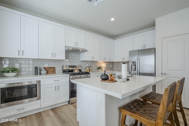 644 N Vine St, Chandler, AZ 85225 - kitchen with appliances with stainless steel finishes, under cabinet range hood, a sink, a breakfast bar, and light countertops