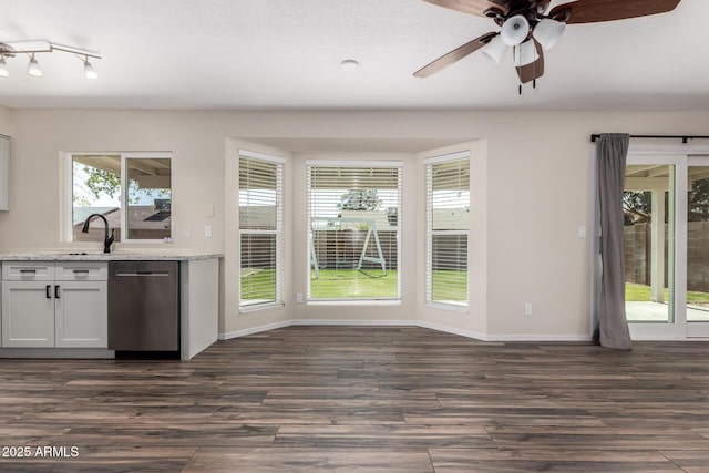 kitchen with dark wood-type flooring, light stone counters, a sink, stainless steel dishwasher, and ceiling fan