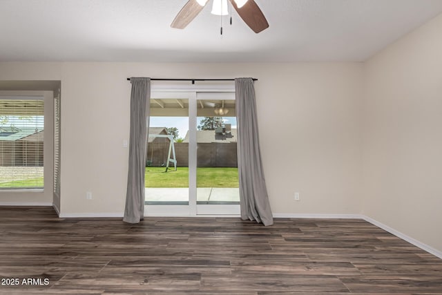 empty room featuring a wealth of natural light, dark wood-style floors, baseboards, and ceiling fan