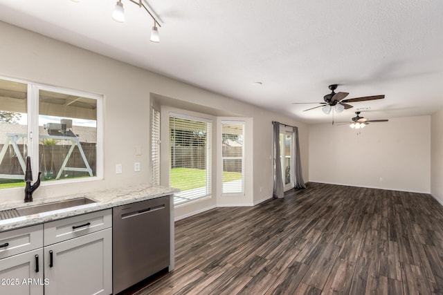 kitchen featuring dark wood-type flooring, a sink, stainless steel dishwasher, light stone countertops, and ceiling fan