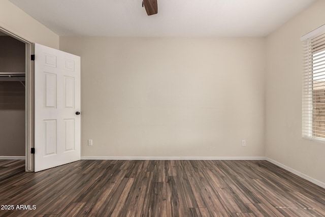 unfurnished bedroom featuring multiple windows, baseboards, and dark wood-style flooring